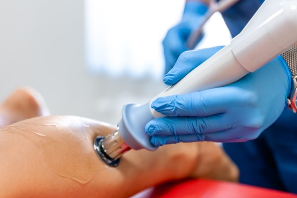 Shock wave therapy, the magnetic field, rehabilitation, physiotherapist doctor performs surgery on a patient's shin, achilles tendon