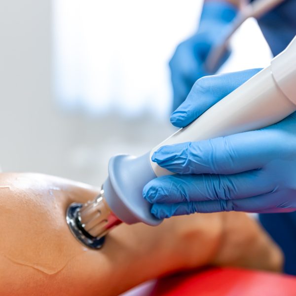 Shock wave therapy, the magnetic field, rehabilitation, physiotherapist doctor performs surgery on a patient's shin, achilles tendon