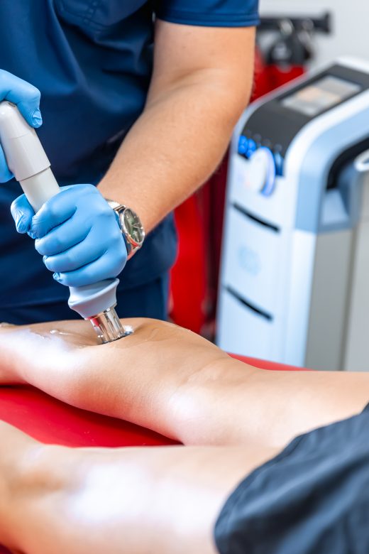 Shock wave therapy, the magnetic field, rehabilitation, physiotherapist doctor performs surgery on a patient's shin, mobility