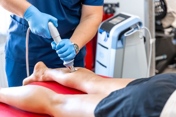 Shock wave therapy, the magnetic field, rehabilitation, physiotherapist doctor performs surgery on a patient's shin, mobility
