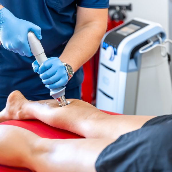 Shock wave therapy, the magnetic field, rehabilitation, physiotherapist doctor performs surgery on a patient's shin, mobility